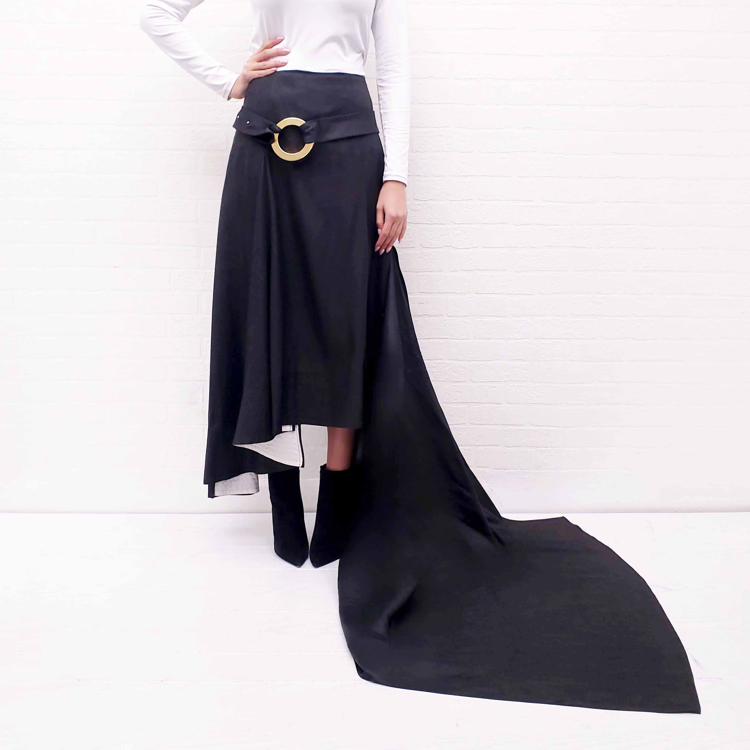 Person wearing a long Celine Runway black skirt with a gold belt on a white background