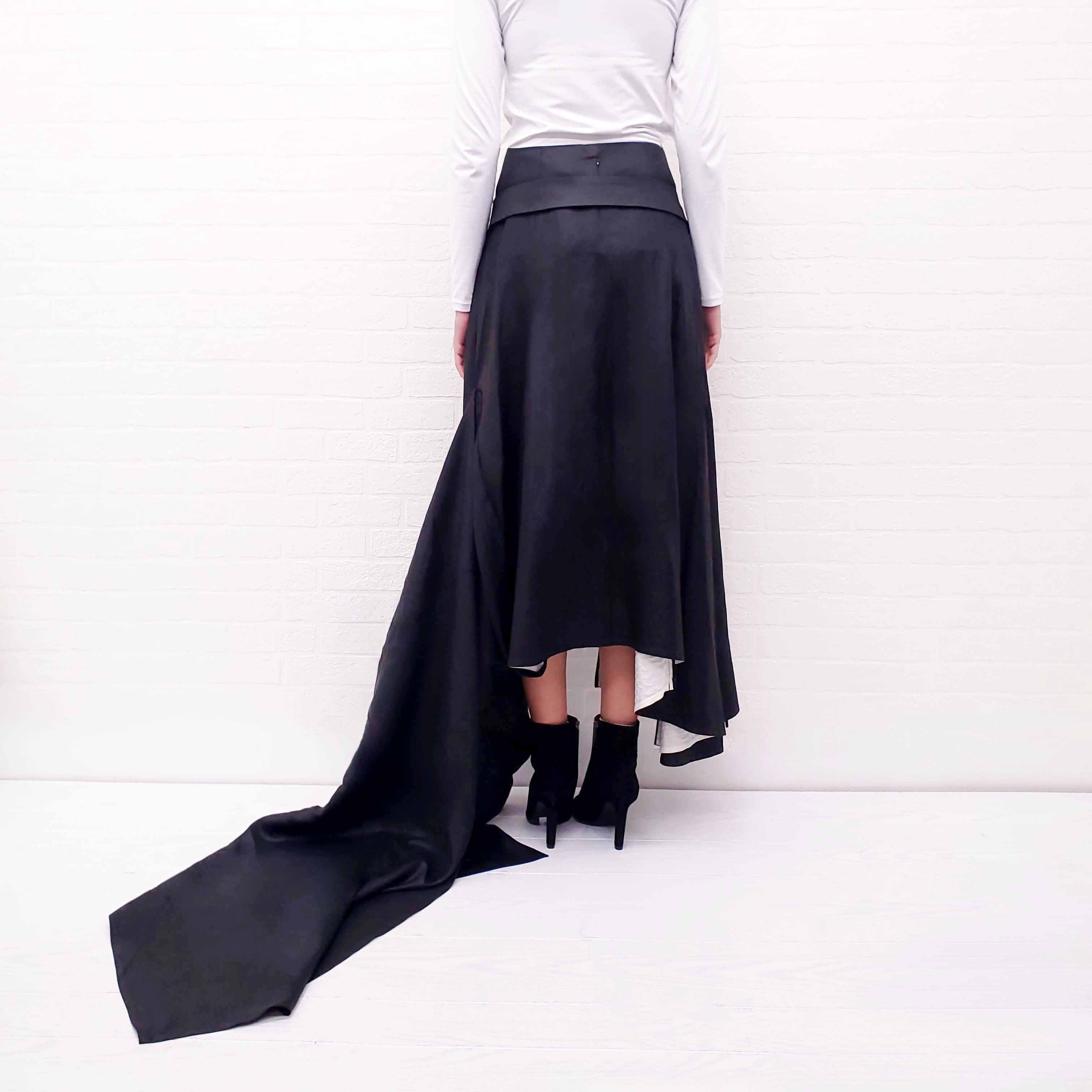 Person wearing a long Celine Runway black skirt with a gold belt on a white background
